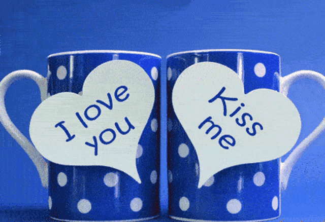 two blue polka dot coffee mugs with speech bubbles that say i love you and kiss me