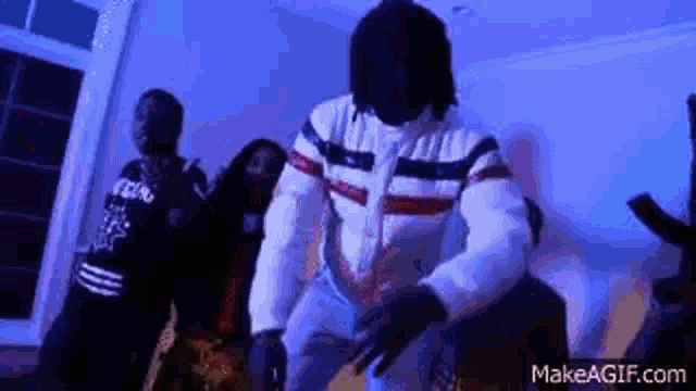 a group of people are dancing in a room with a blue background .