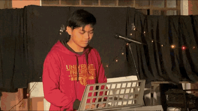 a young man wearing a red university of the philippines sweatshirt