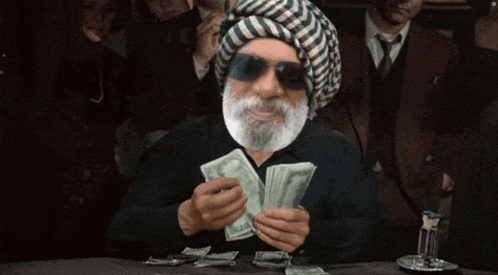 a man with a beard wearing sunglasses and a turban is holding a bunch of money
