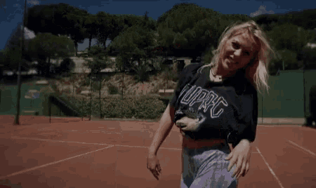 a woman is standing on a tennis court holding a tennis racket .