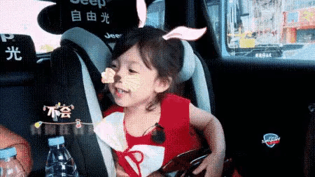 a little girl is sitting in a car seat with a jeep logo on it