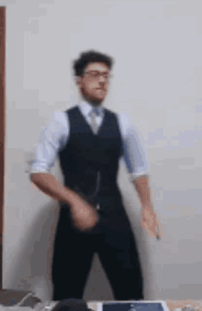 a man in a suit is dancing in front of a wall .