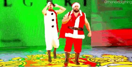 two men dressed as santa claus are dancing on a stage