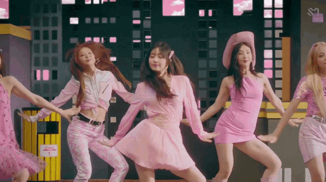 a group of women in pink dresses are dancing together