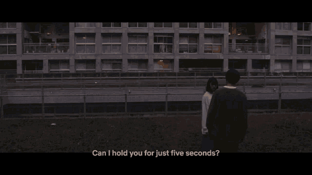 a man and a woman standing in front of a building with the words can i hold you for just five seconds below them
