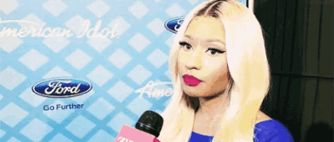 a woman talking into a pink microphone in front of a ford sign