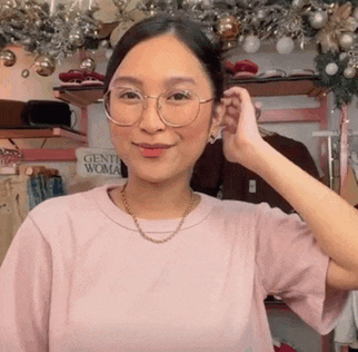 a woman wearing glasses and a pink shirt has a sign that says gentle woman behind her