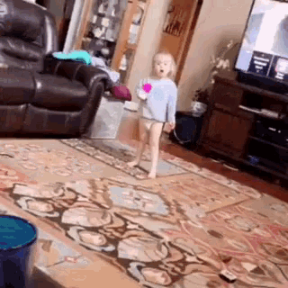 a little girl is standing on a rug in a living room holding a pink balloon .