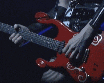 a person is playing a red guitar with white swirls on the neck