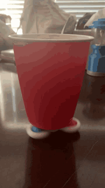 a red cup sits on a wooden table with a blue and white spinning base