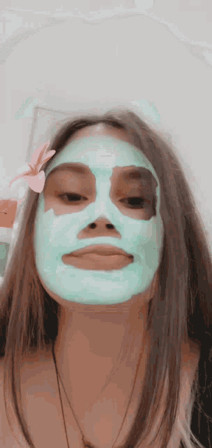 a girl with a green mask on her face with a flower in her hair