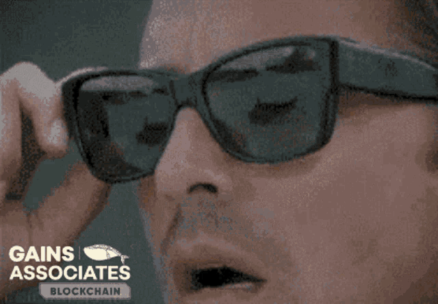 a man wearing sunglasses is looking through a pair of bitcoins