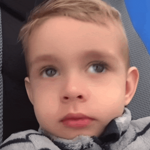 a close up of a young boy 's face with a striped shirt on