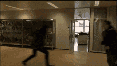 a blurred image of people walking in a hallway with a glass door open