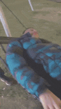 a person in a blue jacket is laying on a swing set