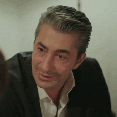 a man in a suit and white shirt is smiling and looking at the camera