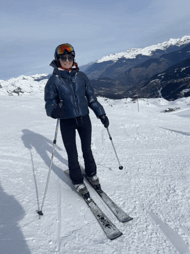 a woman wearing a helmet and goggles is skiing down a snowy hill