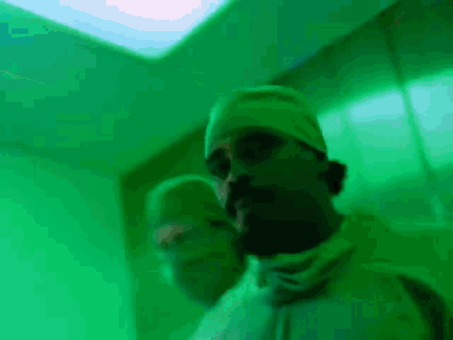 a man in a surgical gown stands in a green room