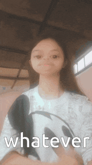 a girl in a mickey mouse shirt is making a funny face and says whatever .