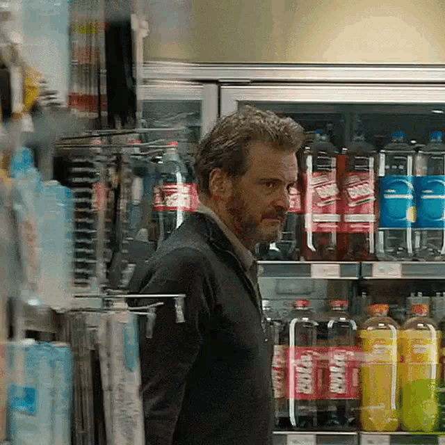 a man is standing in front of a fridge full of sodas including diet coke and pepsi