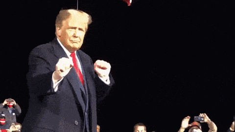 a man in a suit and red tie is giving a fist bump