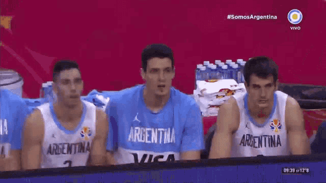 a group of basketball players are cheering in front of a screen that says somos argentina