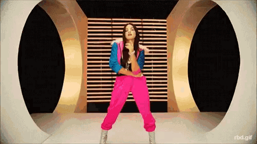 a woman in pink pants and a blue jacket is dancing in front of two circles with rbd.gif at the bottom