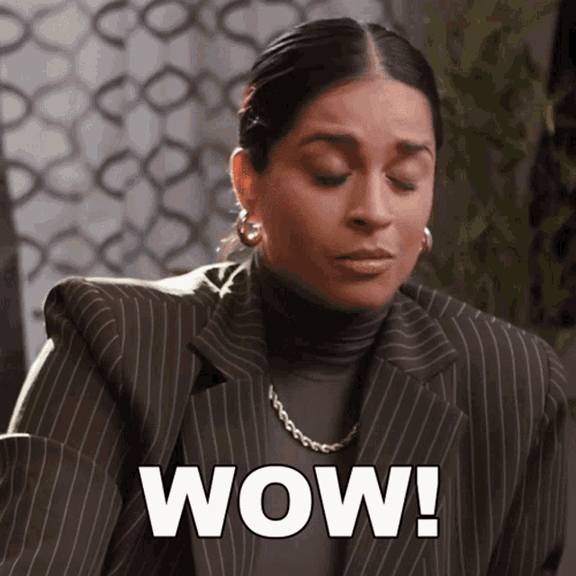a woman wearing a striped suit and a turtleneck says wow