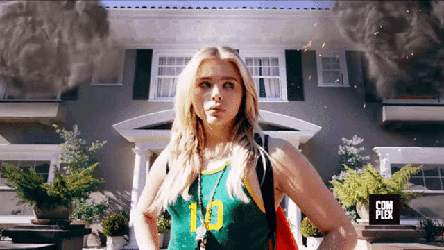 a woman stands in front of a house with a sign that says com plex