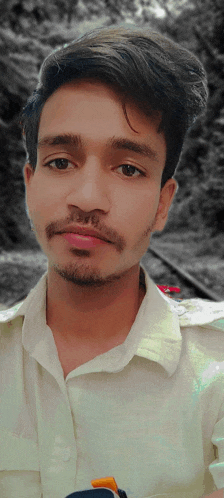 a young man with a beard and a white shirt is looking at the camera