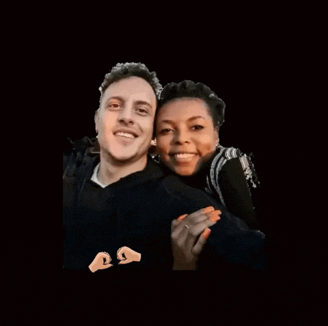 a man and a woman are posing for a picture with a heart made out of their hands