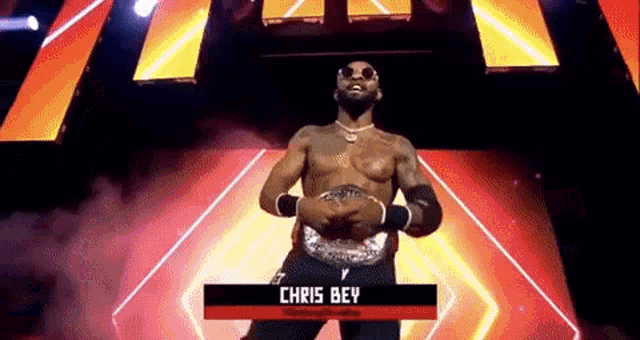 a shirtless wrestler is standing on a stage with a belt around his waist .