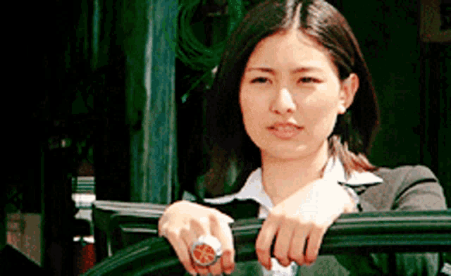 a woman wearing a watch and a ring is leaning on a railing