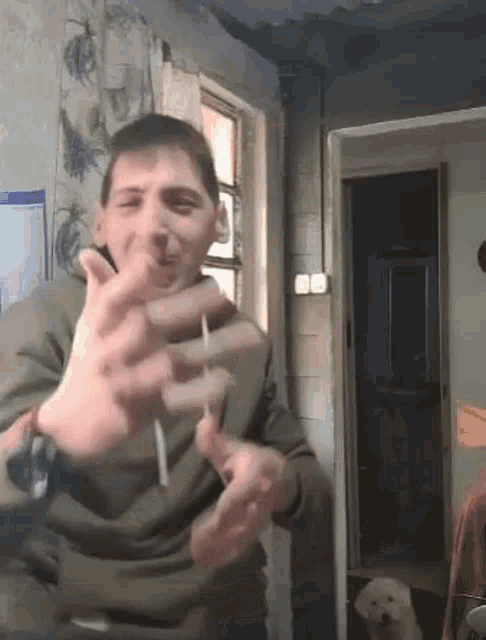 a man is making a funny face while holding a cigarette in his mouth .