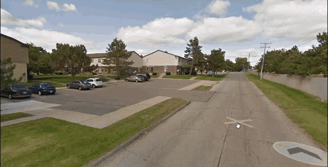 a street with an arrow pointing to the right and a parking lot