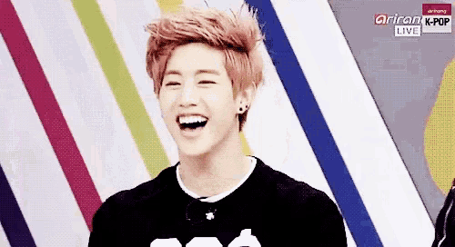 a young man with pink hair is laughing in front of a colorful striped background