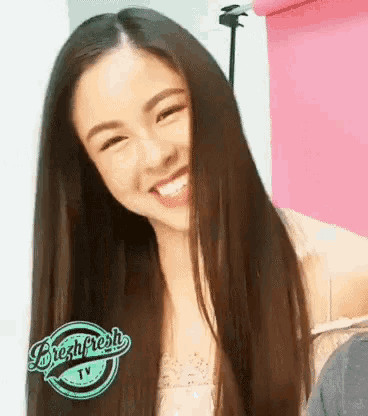 a woman with long hair is smiling in front of a sign that says fresh fresh tv