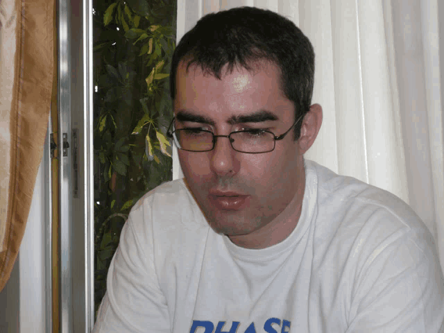 a man wearing glasses and a white shirt that says phase on it