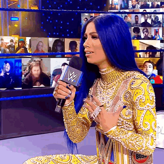 a woman with blue hair is holding a microphone in front of a crowd