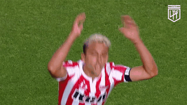 a man in a red and white striped shirt is bending over on a field .