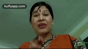 a woman is making a funny face with her mouth open and a red dot on her forehead .
