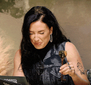 a woman holding a wine glass in front of a laptop that says cosmo