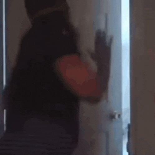 a man is standing in front of a door holding a gun .