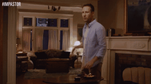a man in a blue shirt is standing in a living room with the hashtag #impastor above him