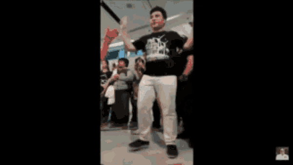 a man in a black shirt is dancing in front of a crowd of people