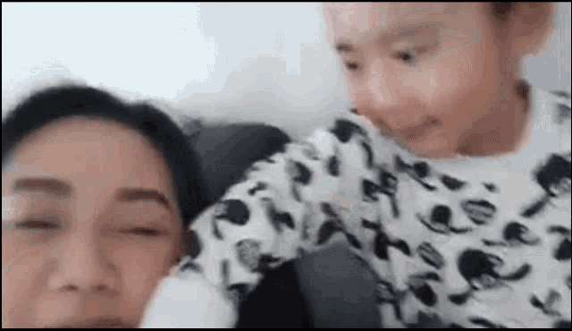 a woman and a child are sitting on a couch and looking at each other .