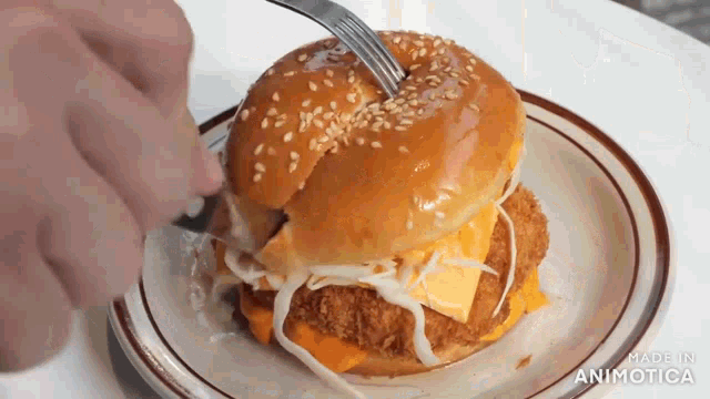 a person is cutting into a hamburger with a fork on a plate .