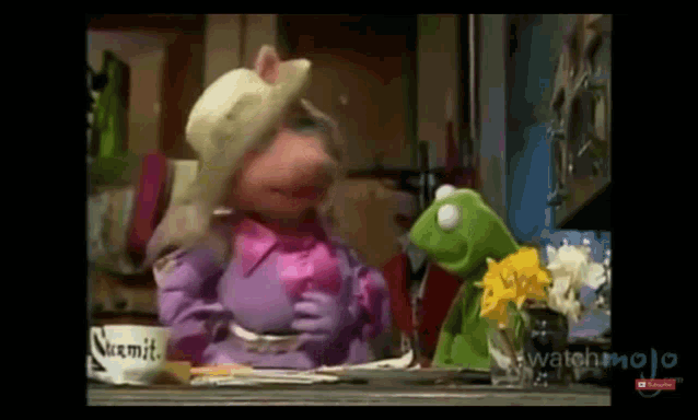 mrs. piggy and kermit the frog are sitting at a table .