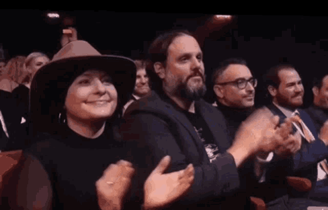 a group of people are sitting in a theater and clapping their hands .